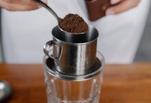 a person pouring a coffee into a glass cup