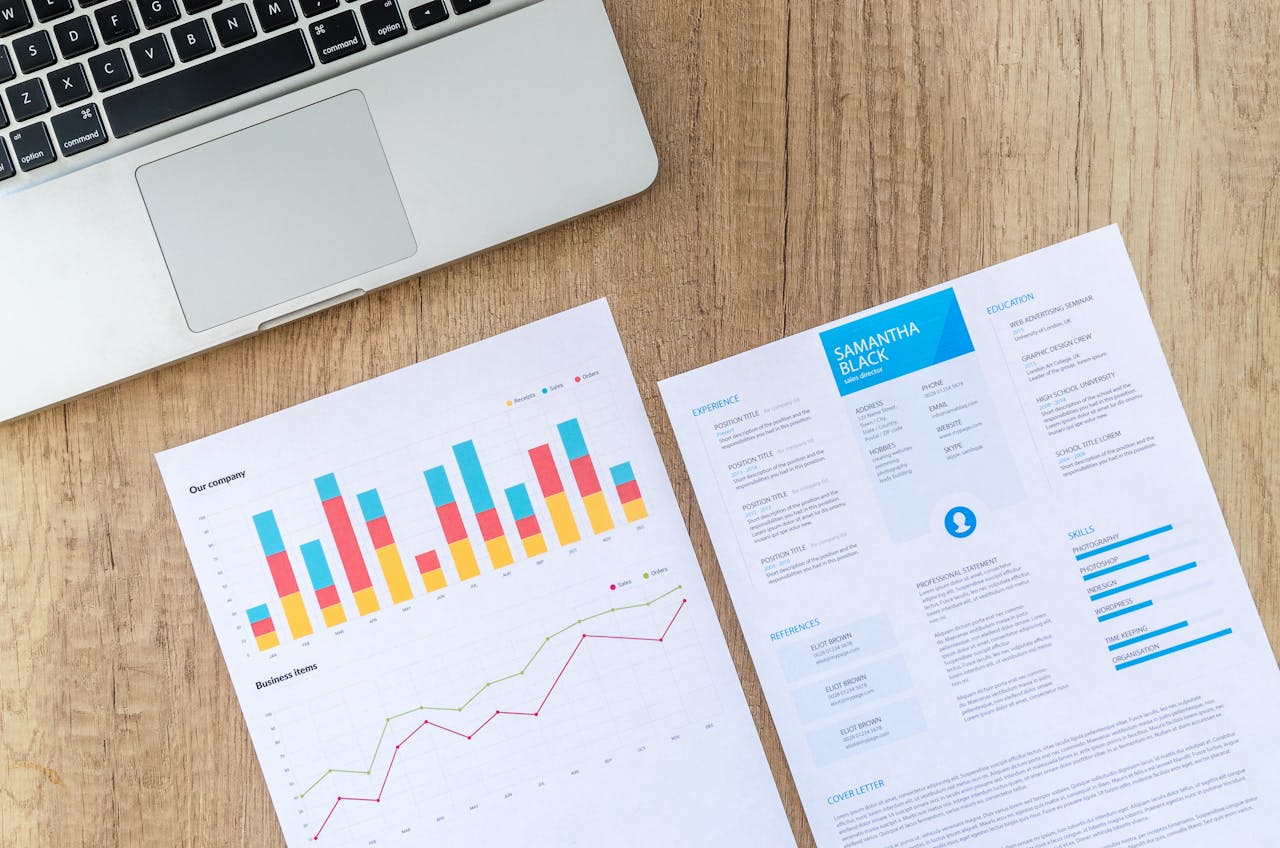 Business report with colorful charts and resume on wooden desk, illustrating data analysis and professional skills